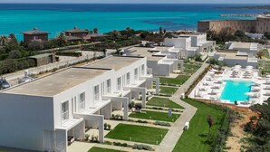 A resort with modern white buildings, a swimming pool, and a view of the ocean. - Capo Falcone Charming Apartment by Interhome (Stintino)