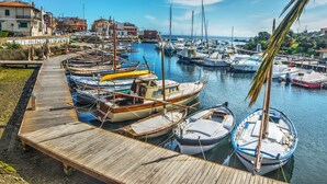 A marina with various boats docked along a wooden pier, surrounded by buildings and a clear sky. - Capo Falcone Charming Apartment by Interhome (Stintino)