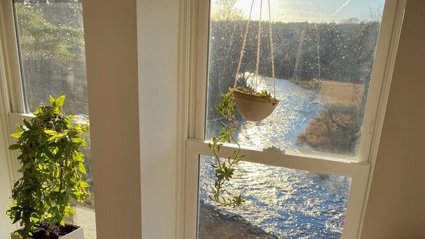 A room with a large window, a potted plant on the sill, and a view of a snowy landscape outside.