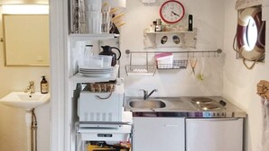 Une cuisine de taille réduite, équipée d’un évier, d’une cuisinière et d’étagères pour le rangement.
