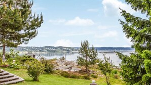 Une zone herbeuse avec un petit étang, entourée d’arbres, d’où l’on peut admirer un lac et des collines lointaines.
