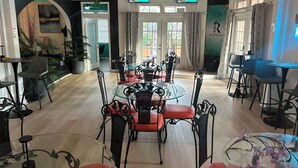 A dining area with a glass table and black metal chairs, a ceiling fan, and a TV displaying a welcome message.