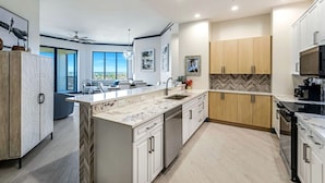 Una cucina moderna con una grande isola, mobili bianchi e una parete di fondo con decorazione a spina di pesce.