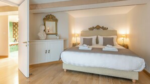 A bedroom with a large bed, a dresser, a mirror, and two bedside lamps.