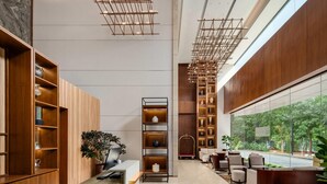 A modern reception area with wooden shelving, a reception desk, and seating. - Ramada Encore by Wyndham Gurugram Dwarka Expressway (Gurugram)