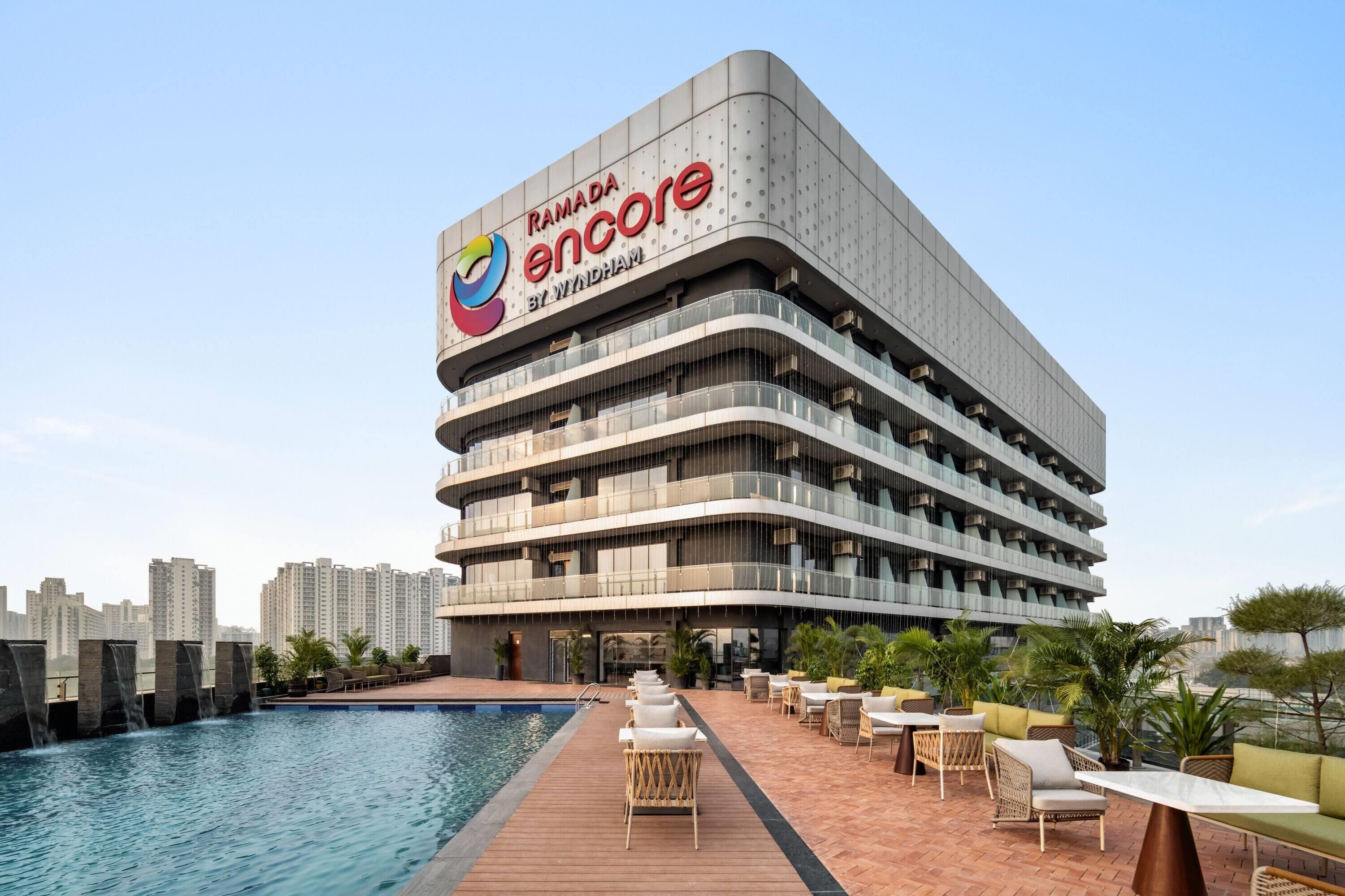 Un hôtel à plusieurs étages doté d’une piscine, d’un espace extérieur aménagé et offrant une vue sur le panorama urbain.