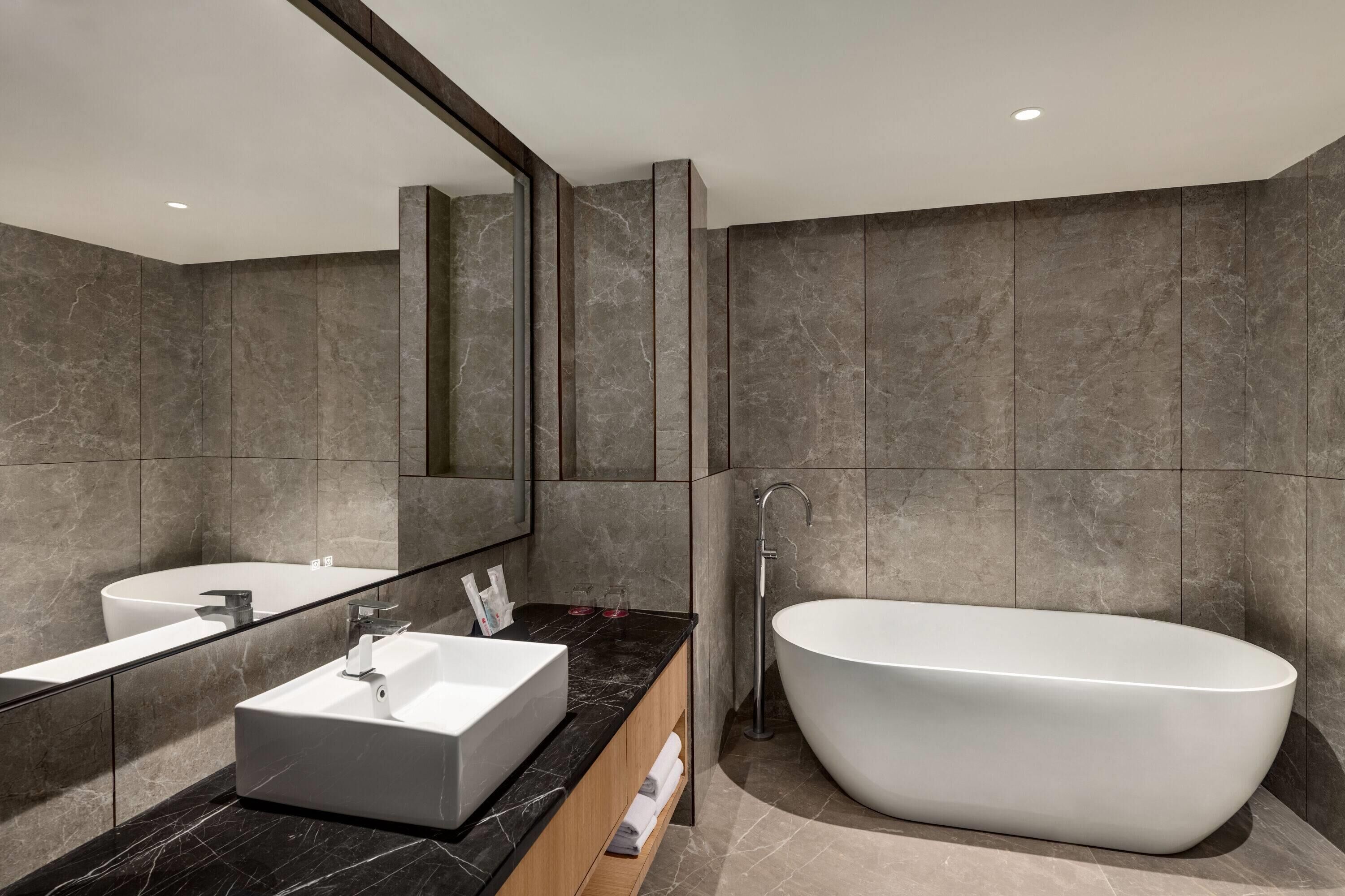 Une salle de bain moderne avec une baignoire sur pieds, un grand miroir et un meuble-lavabo.