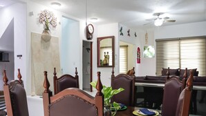 A dining area with wooden chairs, a dining table, a vase with a plant, and a clock on the wall. - 27 Ely House (Cancún)