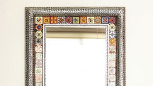 A mirror with a decorative frame featuring a variety of tile patterns. - 27 Ely House (Cancún)