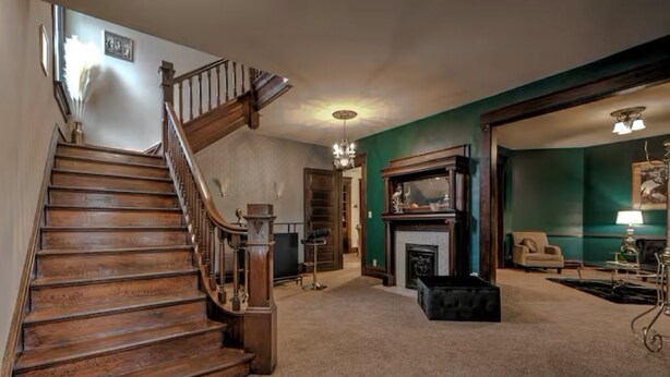 A staircase leading to a landing with a fireplace, a sofa, and a lamp.