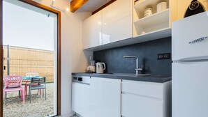Una cocina moderna con armarios blancos, lavavajillas integrado y refrigerador.