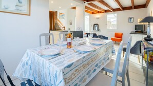 Un comedor con una mesa lista para cuatro personas, una botella de vino y un cuadro en la pared.