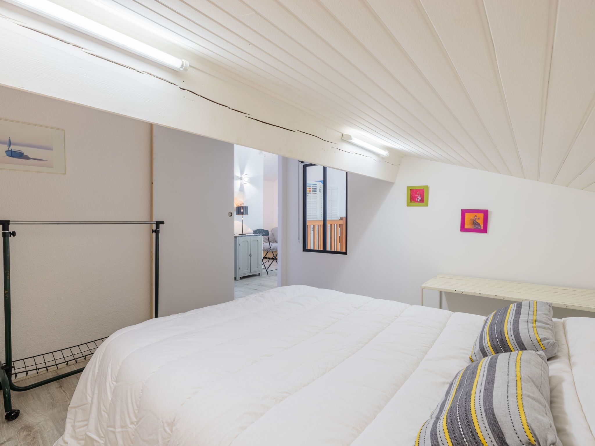 Un dormitorio con cama, mesita de noche, radiador y ventana.