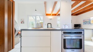 Una cocina moderna con isla central, horno empotrado y vigas de madera.