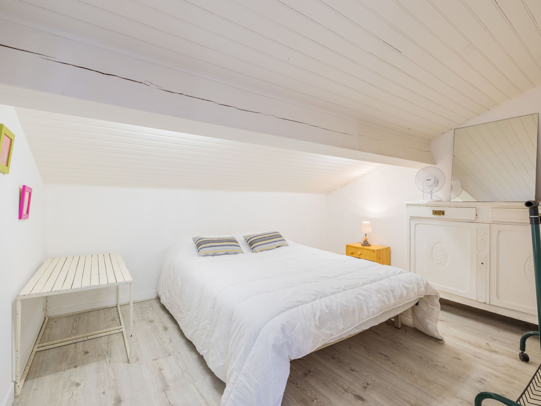A bedroom with a bed, bedside table, and a mirror.