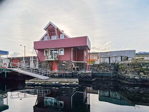 Un edificio rojo con balcón, pared de piedra y un muelle.