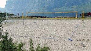 Una rete da pallavolo sulla spiaggia con montagne sullo sfondo.