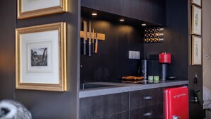 A modern kitchen with dark cabinetry, a red refrigerator, and framed pictures on the wall. - Domes at Catskills a lakefront glamping adventure for adults (Swan Lake)