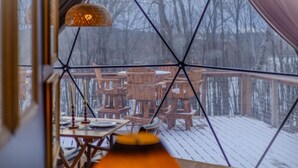 A wooden deck with outdoor furniture and a snow-covered ground. - Domes at Catskills a lakefront glamping adventure for adults (Swan Lake)
