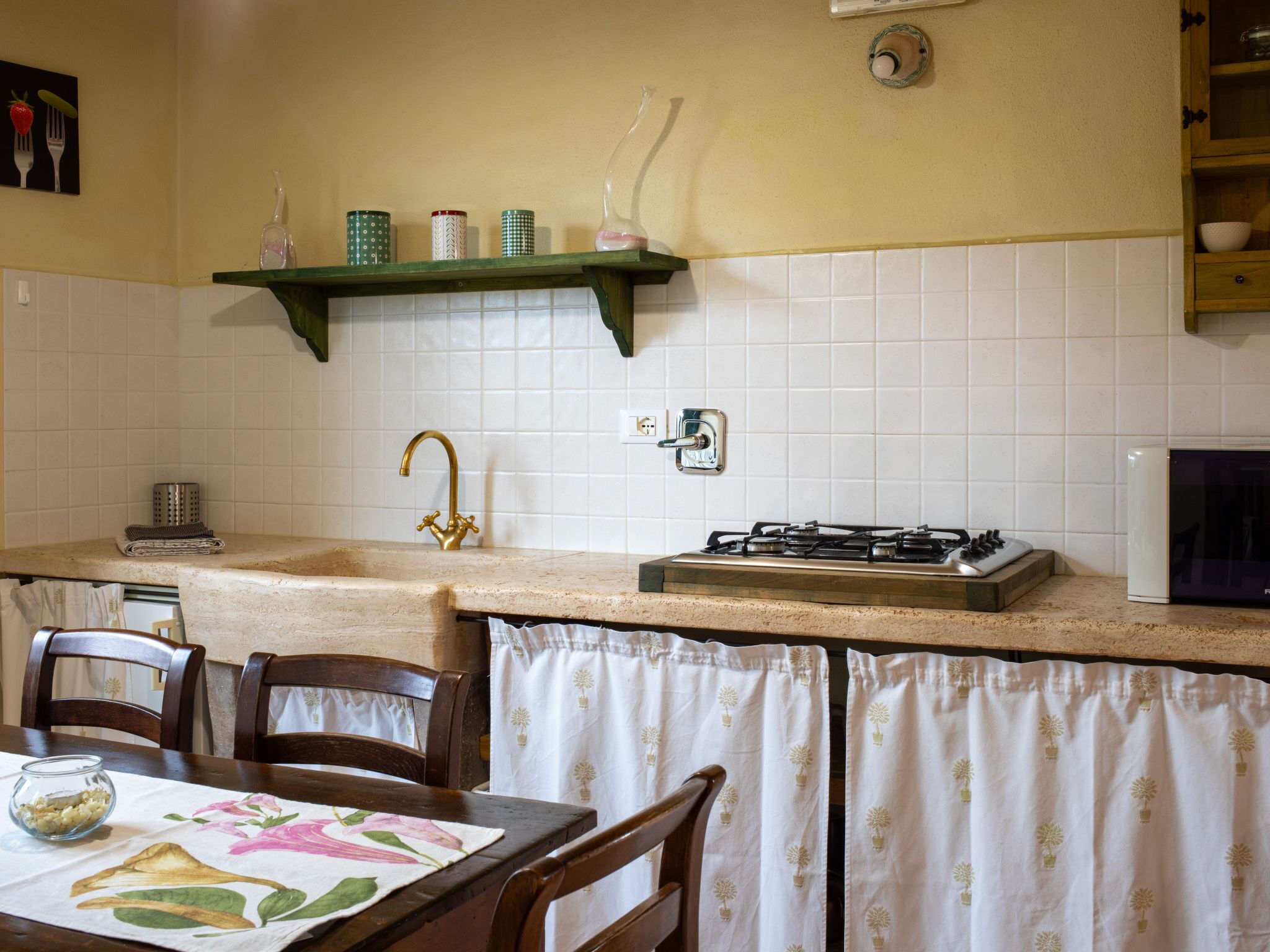 Une cuisine équipée d’une cuisinière à gaz, d’un évier et d’une étagère verte située au-dessus de l’évier.