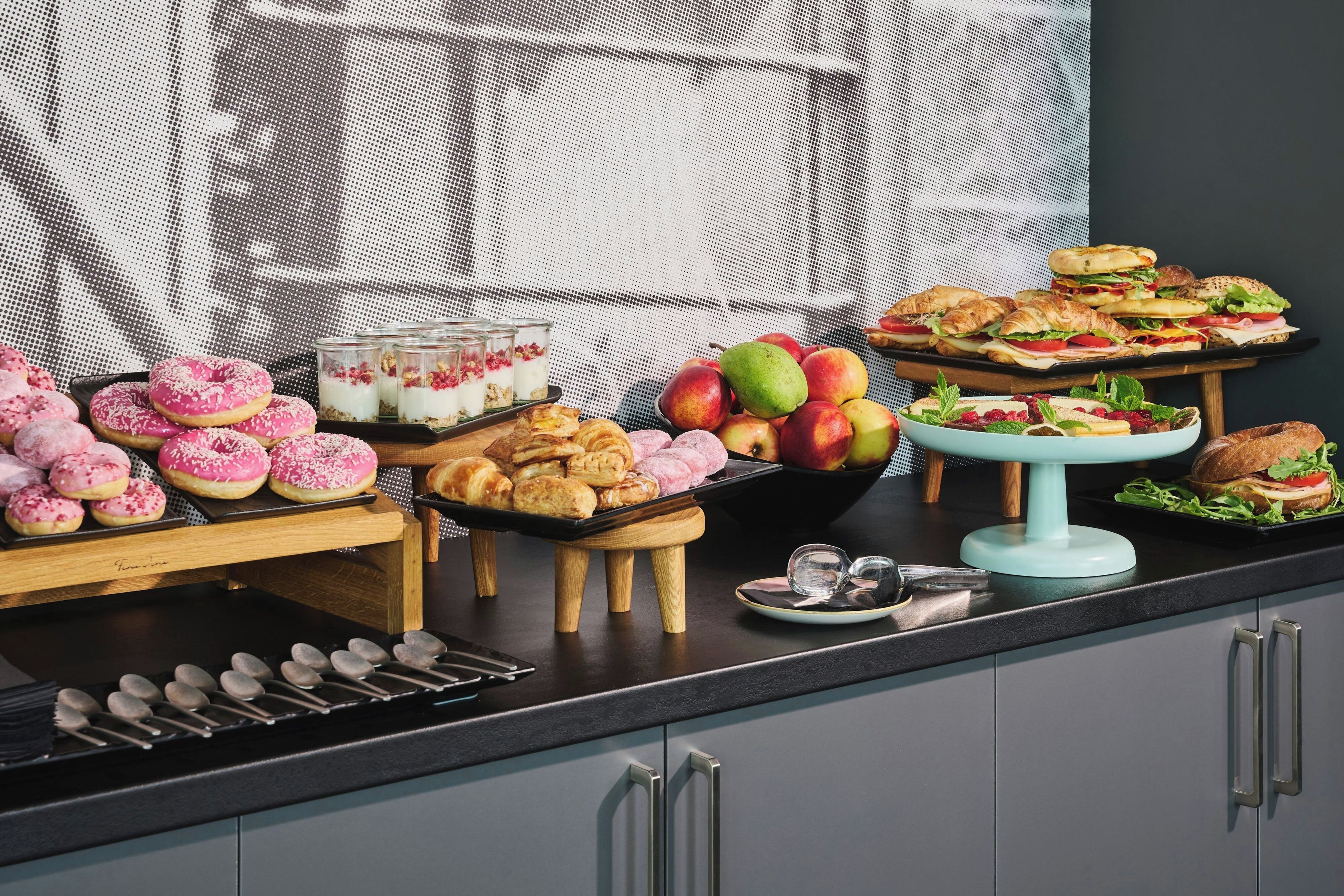 Una mesa de bufé con diferentes opciones de comida, incluyendo pasteles, frutas y sándwiches.
