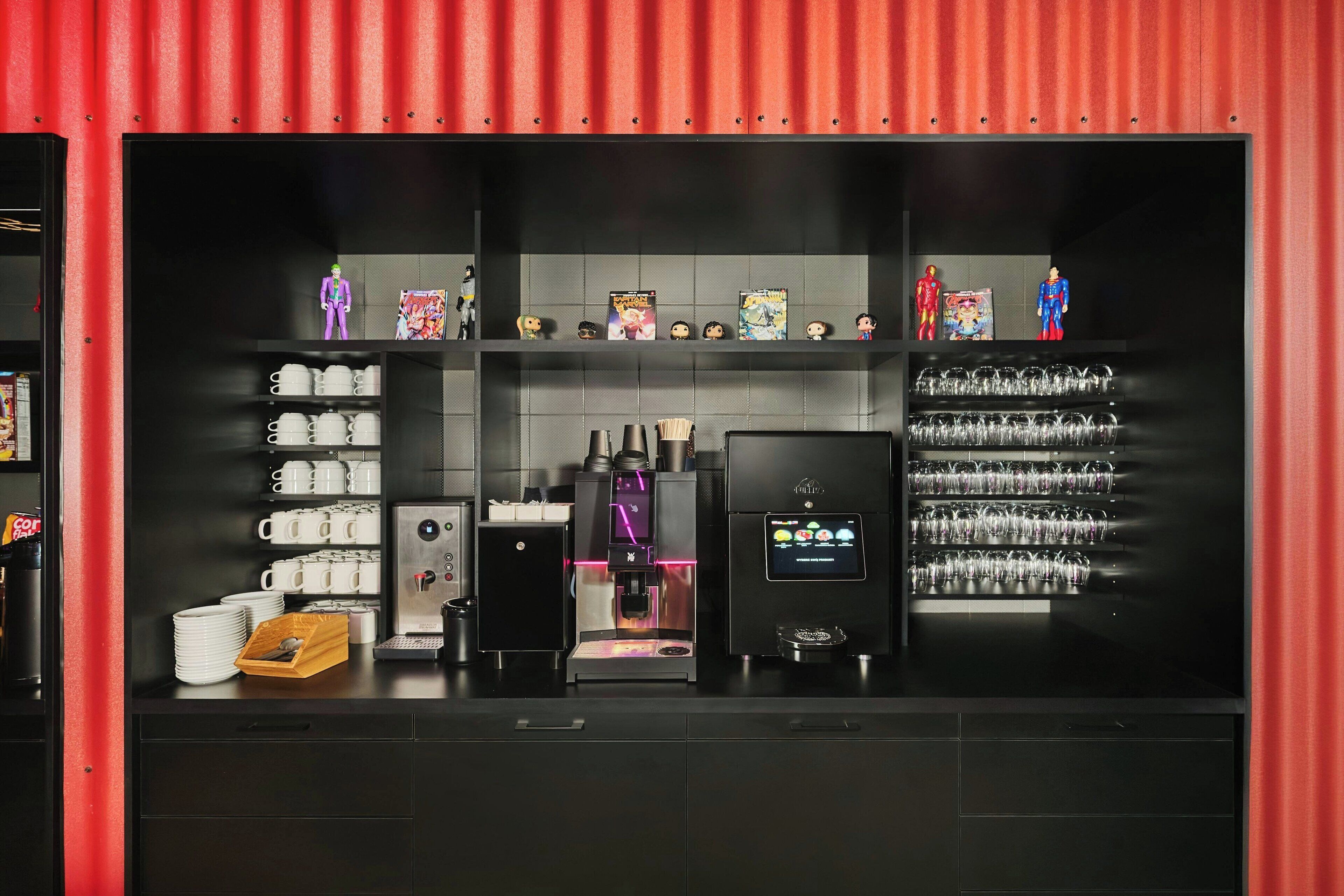 A modern coffee shop with a coffee machine, shelves with cups, and a display of figurines.