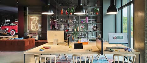 A modern office space with a large desk, chairs, a computer, and a bookshelf.