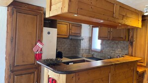 A kitchen with wooden cabinets, a black countertop, and a backsplash with a diamond pattern. - Chalet soleil ski in ski out (La rosiere)