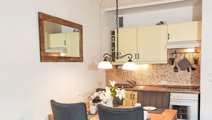 A dining area with a wooden table and chairs, a mirror on the wall, and a kitchen with cabinets and a stove. - Apartment Elwi by Interhome (Hahnenklee)