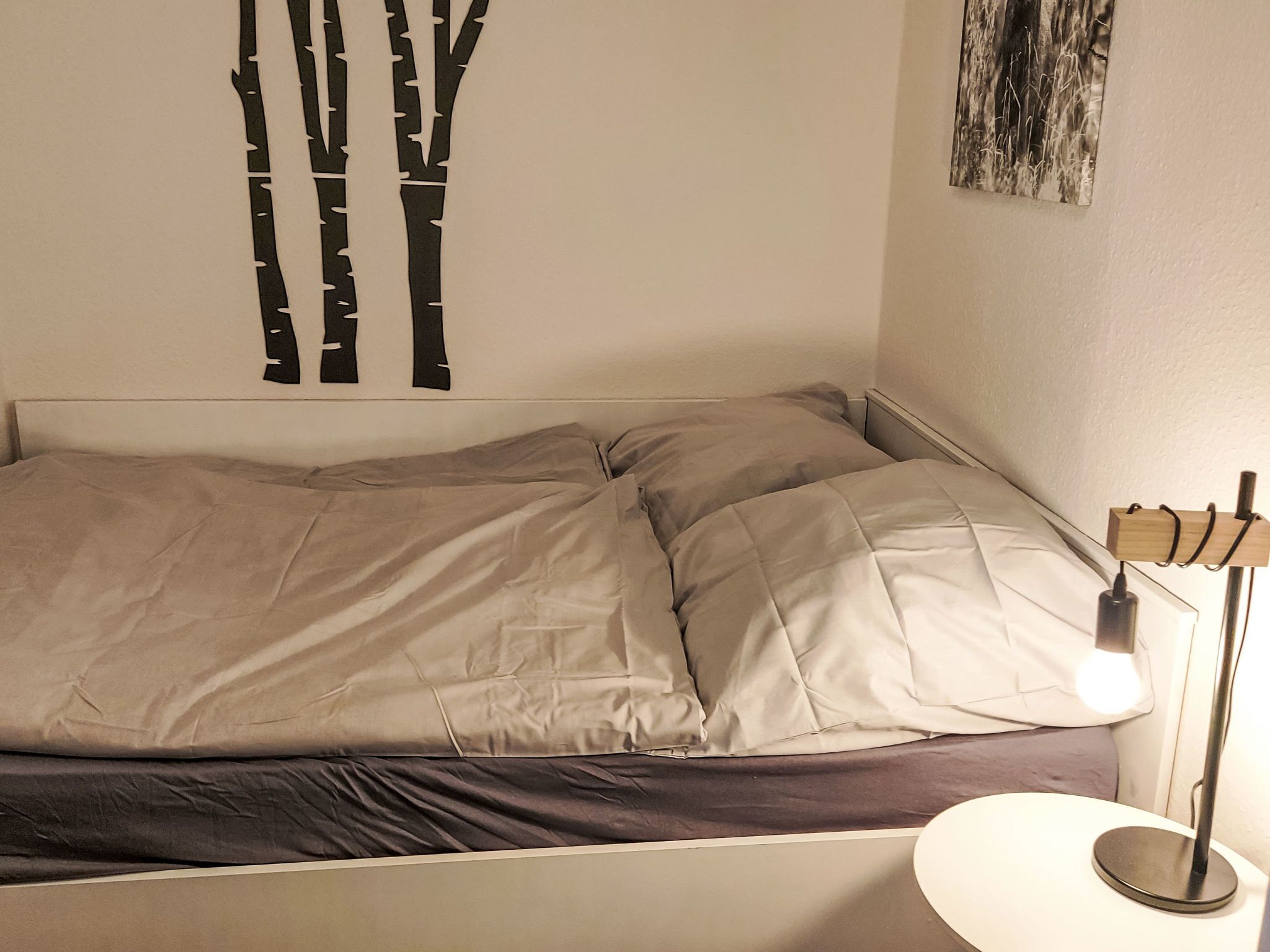 A bed with a headboard, a bedside table with a lamp, and a wall decoration.