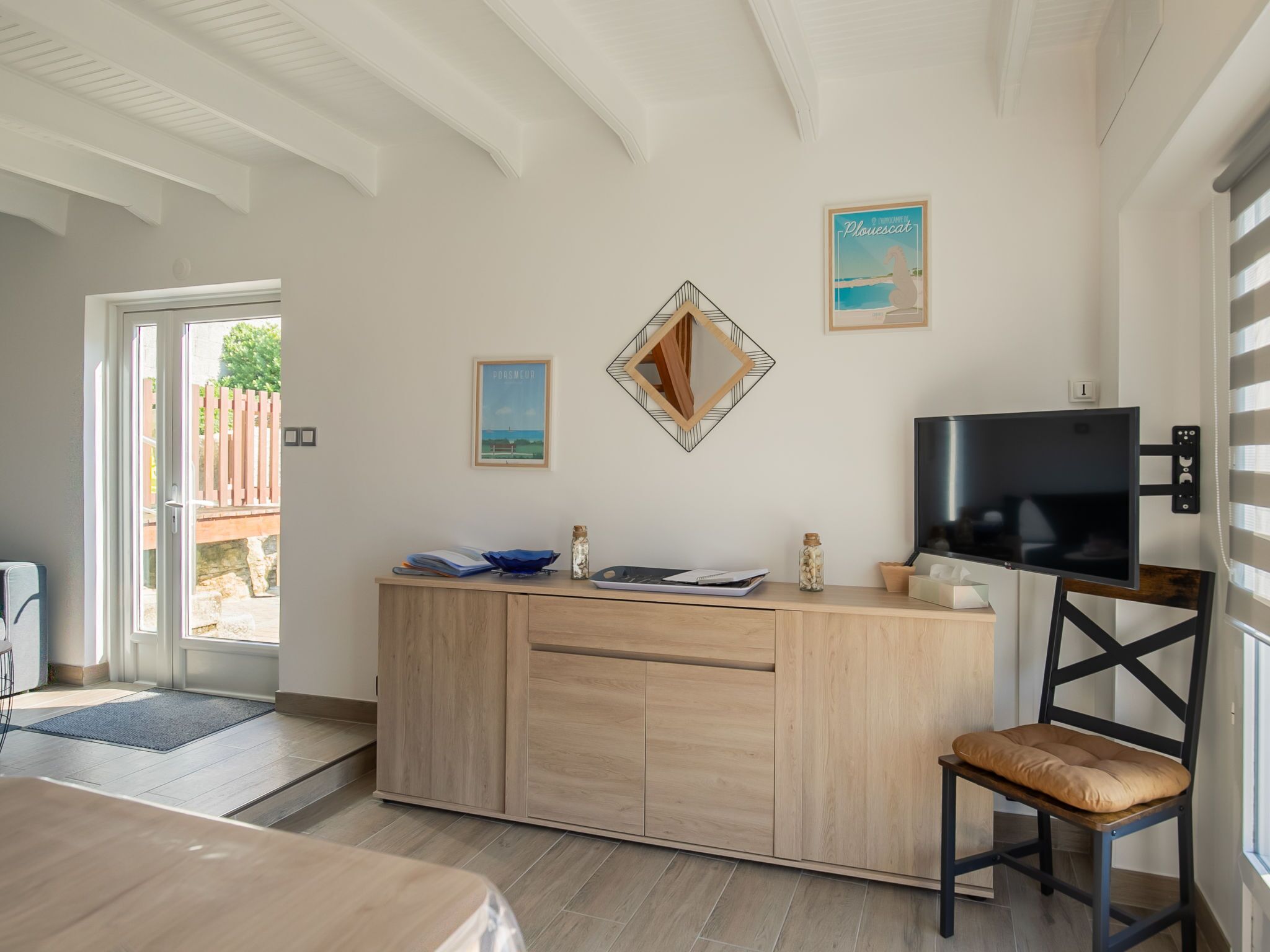 A modern room with a wooden cabinet, a TV mounted on the wall, and a chair.