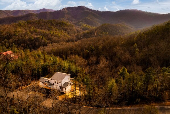 Une maison entourée d’une forêt dense et de collines.