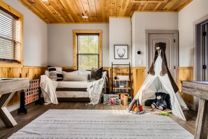 Une pièce confortable avec un lit, un espace de jeux et une tente.