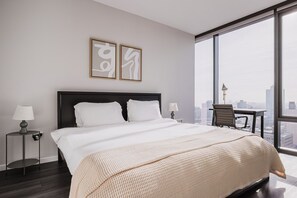 Relax in a serene space with a large bed, dark headboard, and city views.