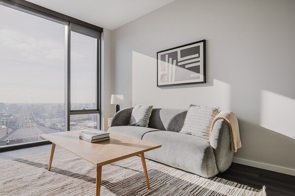 Enjoy a panoramic city view from this stylish living room with a sofa, side table, and artwork.