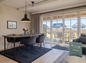 Un espace repas moderne avec une table en bois, des chaises noires et un luminaire suspendu.
