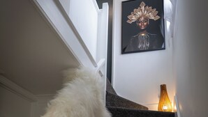 A staircase with a fluffy white object at the bottom, a framed artwork on the wall, and a lit vase on the landing. - Norwich - House - Sleeps 7 - Parking - Garden (Norwich)
