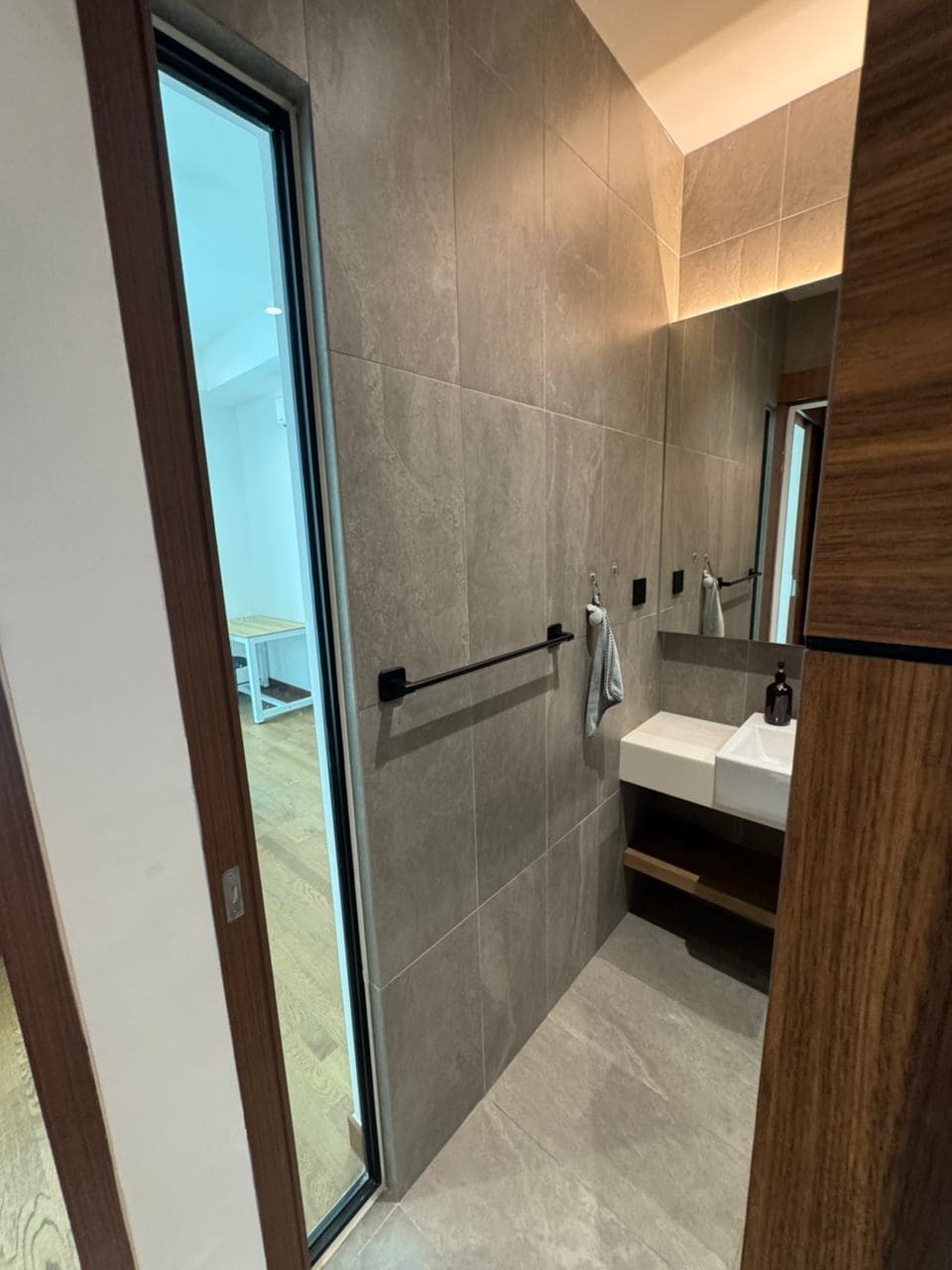 A modern bathroom with a glass door, a white sink, and a mirror.