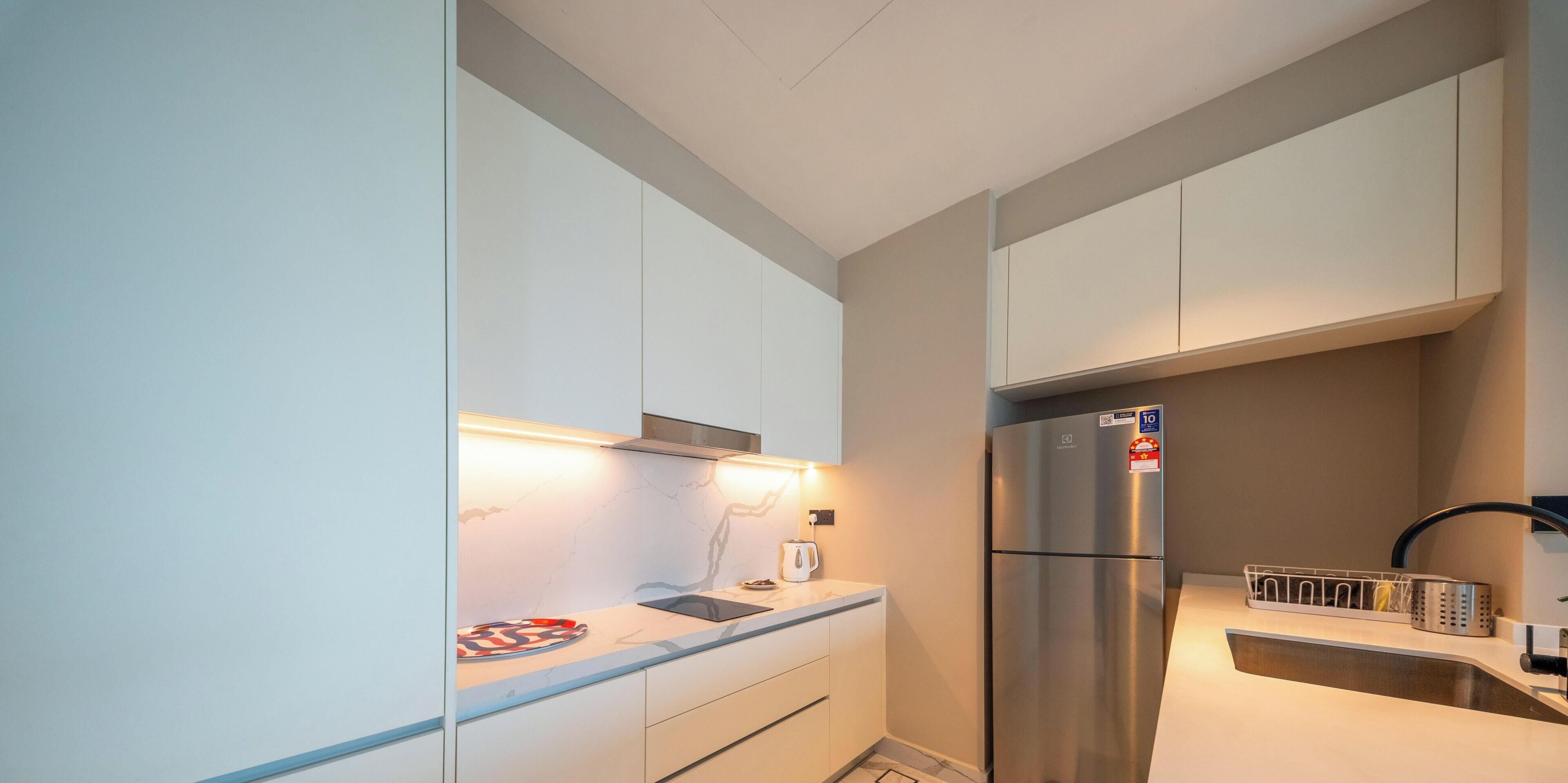 A modern kitchen with white cabinets, a stainless steel refrigerator, and a built-in oven.
