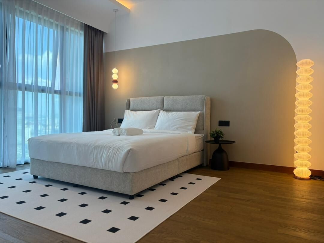 Une chambre moderne avec un grand lit, un tapis à motifs et un luminaire mural original.