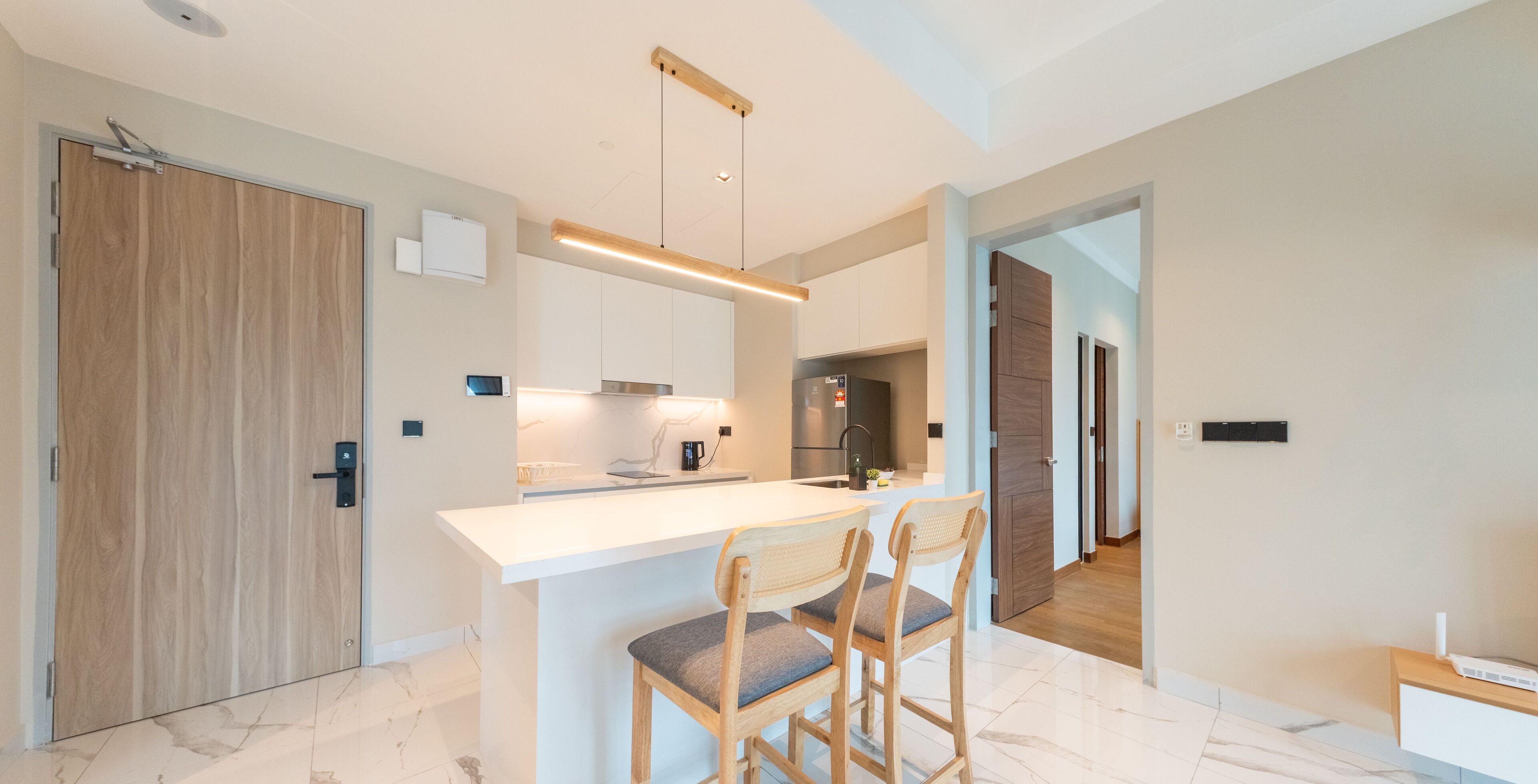 Een moderne keuken met een centraal eiland, houten stoelen en een ingebouwde oven.