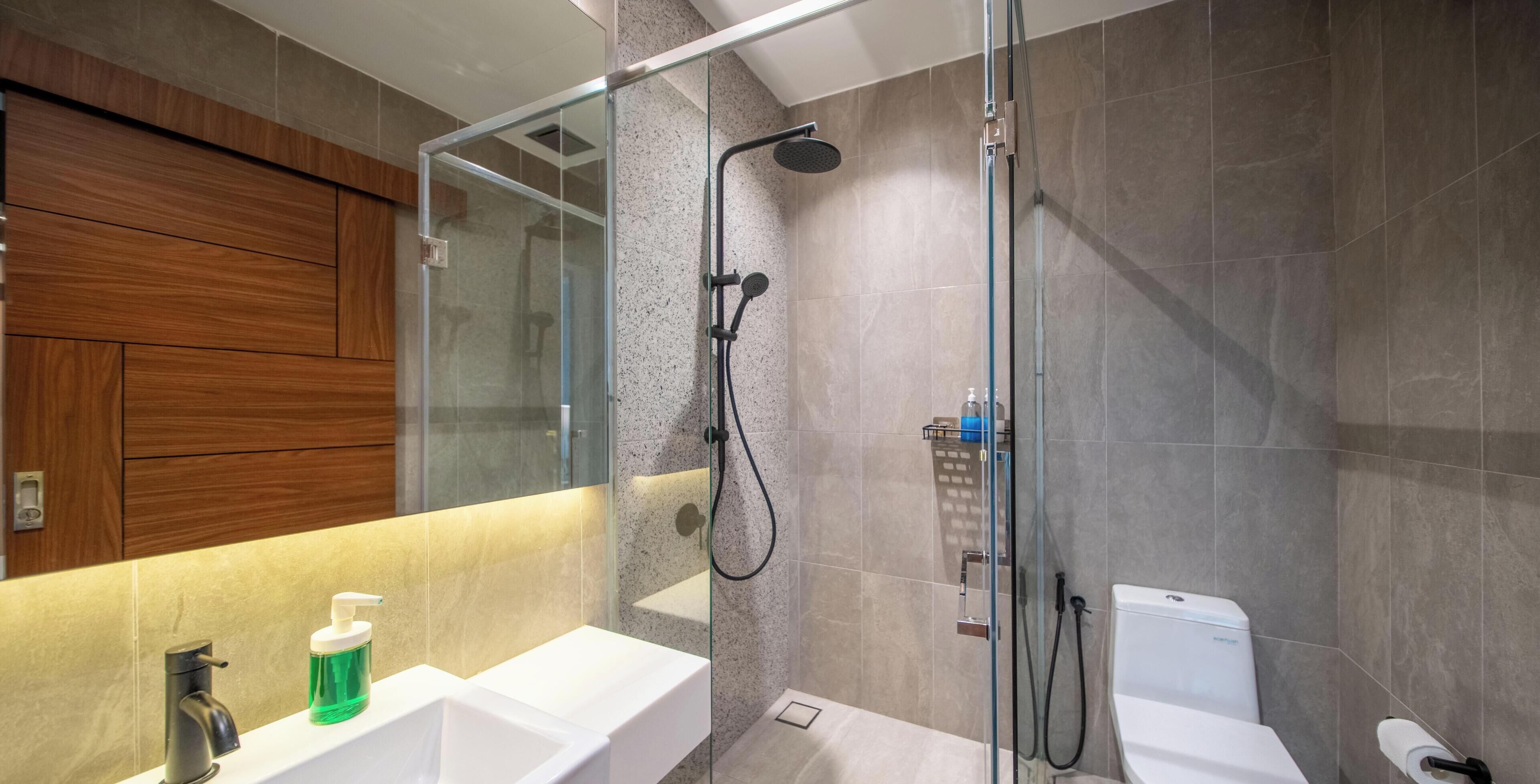 A modern bathroom with a glass-enclosed shower, a white sink, and a toilet.