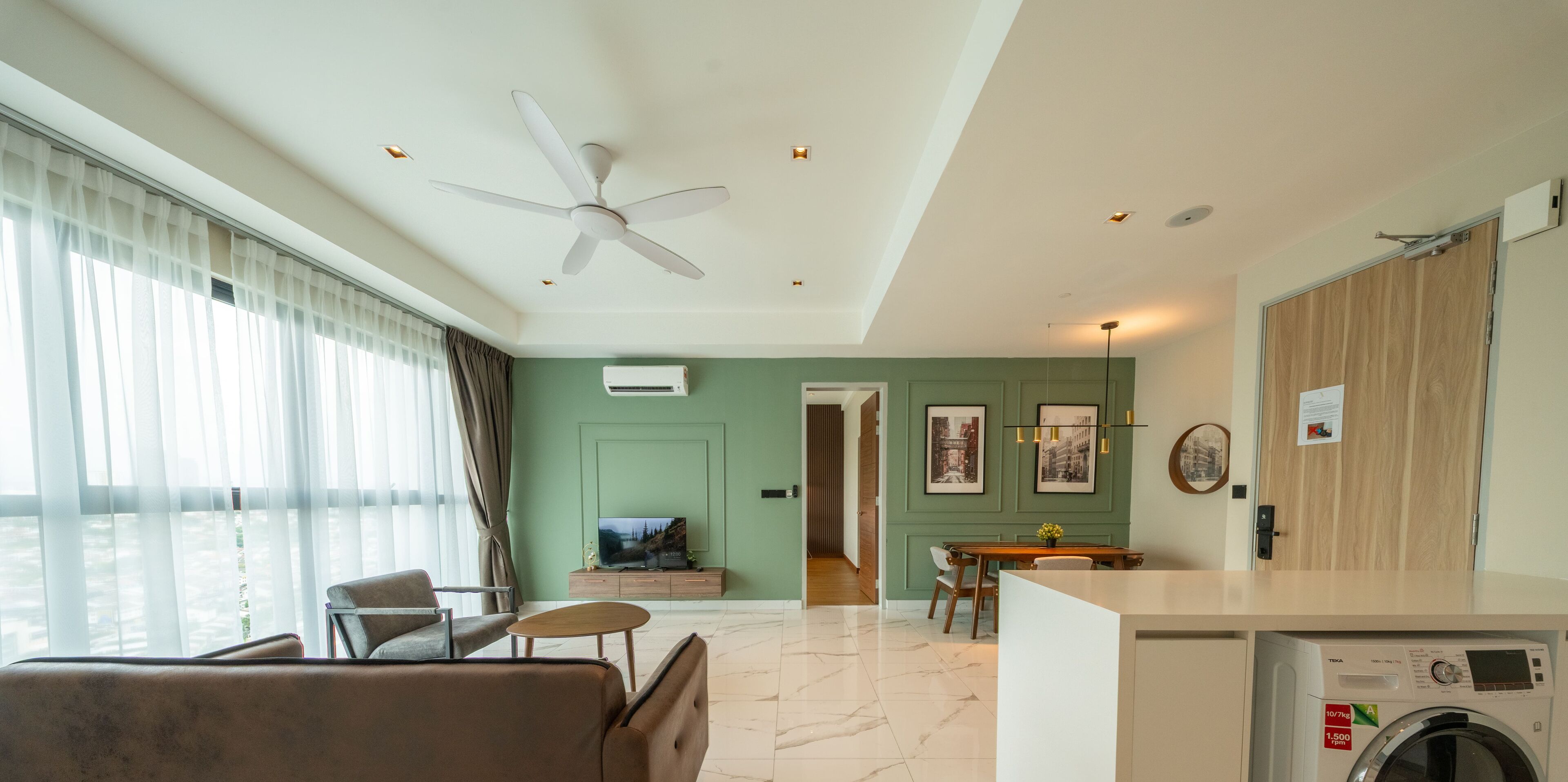A modern living room with a ceiling fan, a TV, a dining area, and a washing machine.