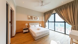 Relax in a spacious room with a large bed, ceiling fan, and city views through large windows.