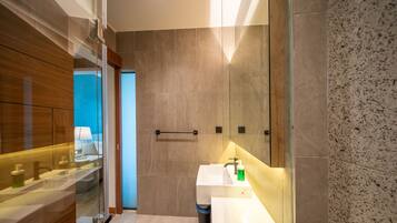 Een moderne badkamer met een glazen wand, een witte wastafel en een spiegel.