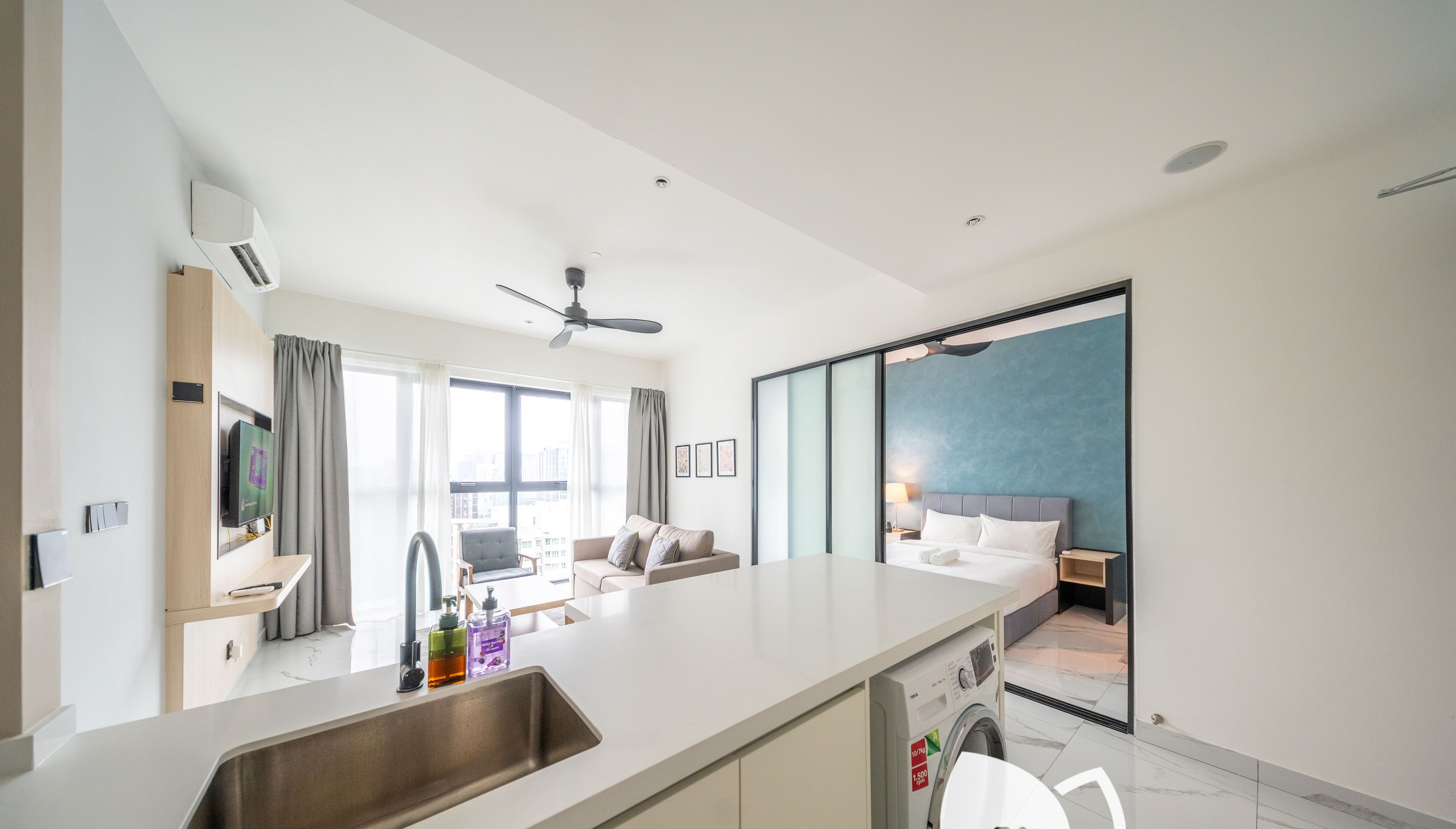 A modern kitchen with a built-in dishwasher, a large window, and a view of the living area.