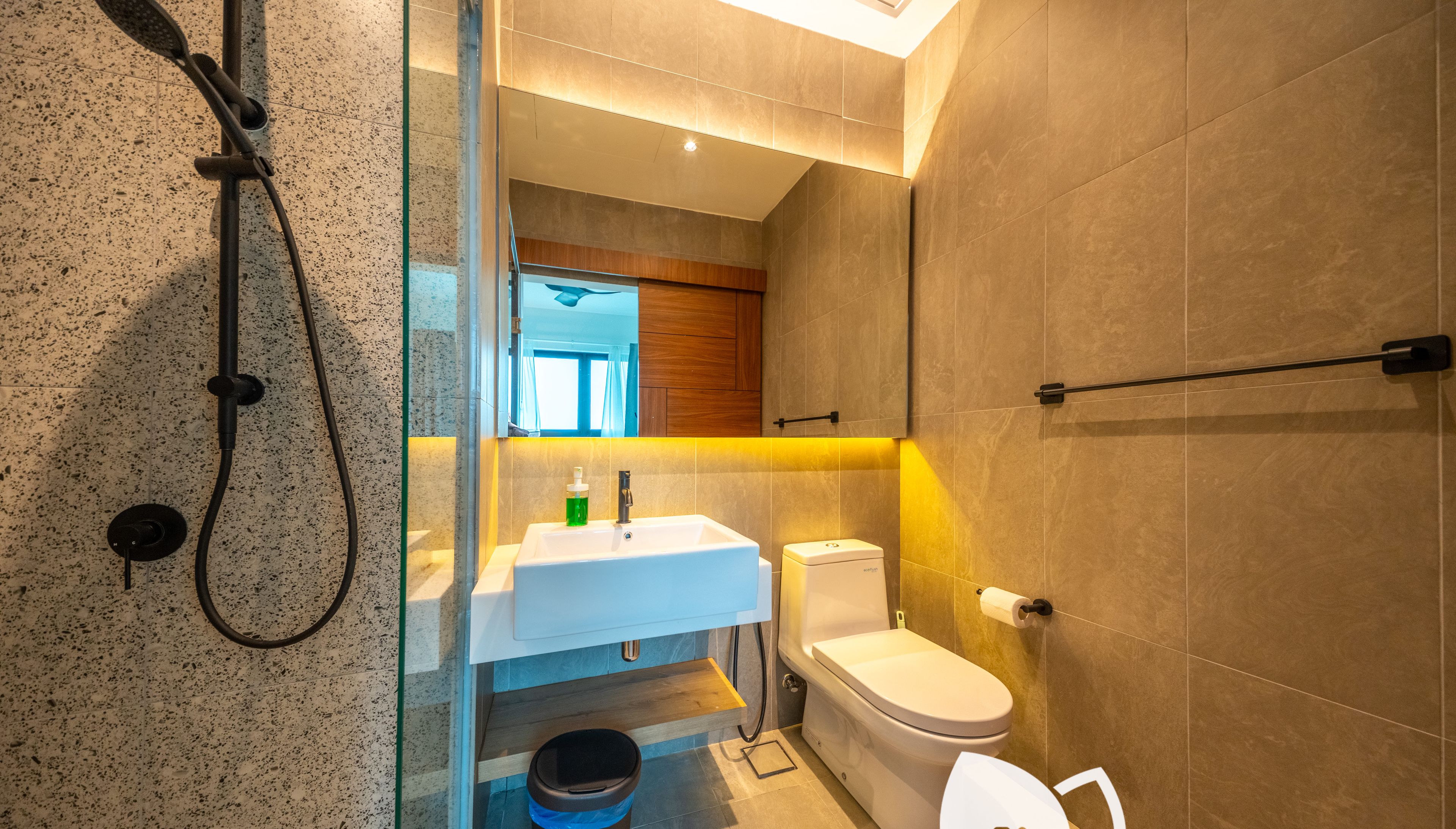 Een moderne badkamer met een douchecabine van glas, een witte wastafel en een toilet.