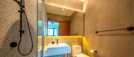 Een moderne badkamer met een douchecabine van glas, een witte wastafel en een toilet.