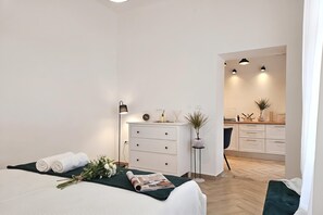 Ein modernes Schlafzimmer mit einem Bett, einem Schminktisch, einem Nachttisch und einer kleinen Topfpflanze.