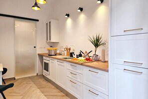 Cozinha moderna com armários brancos, bancada de madeira e diversos utensílios de cozinha.